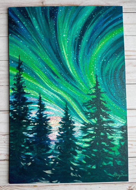 A vertical canvas painting of the northern lights over a forest of pine trees, displayed on a light-colored wooden plank background.