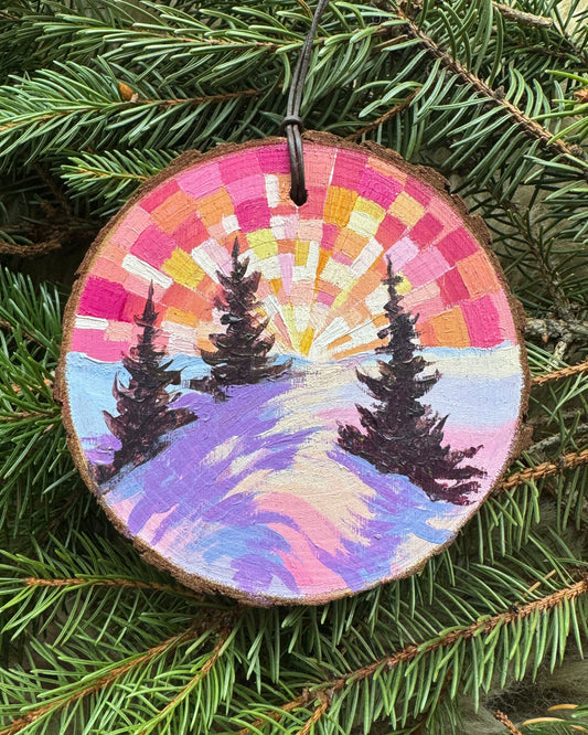Decorative ornament with a colorful spiral design on a green pine branch.