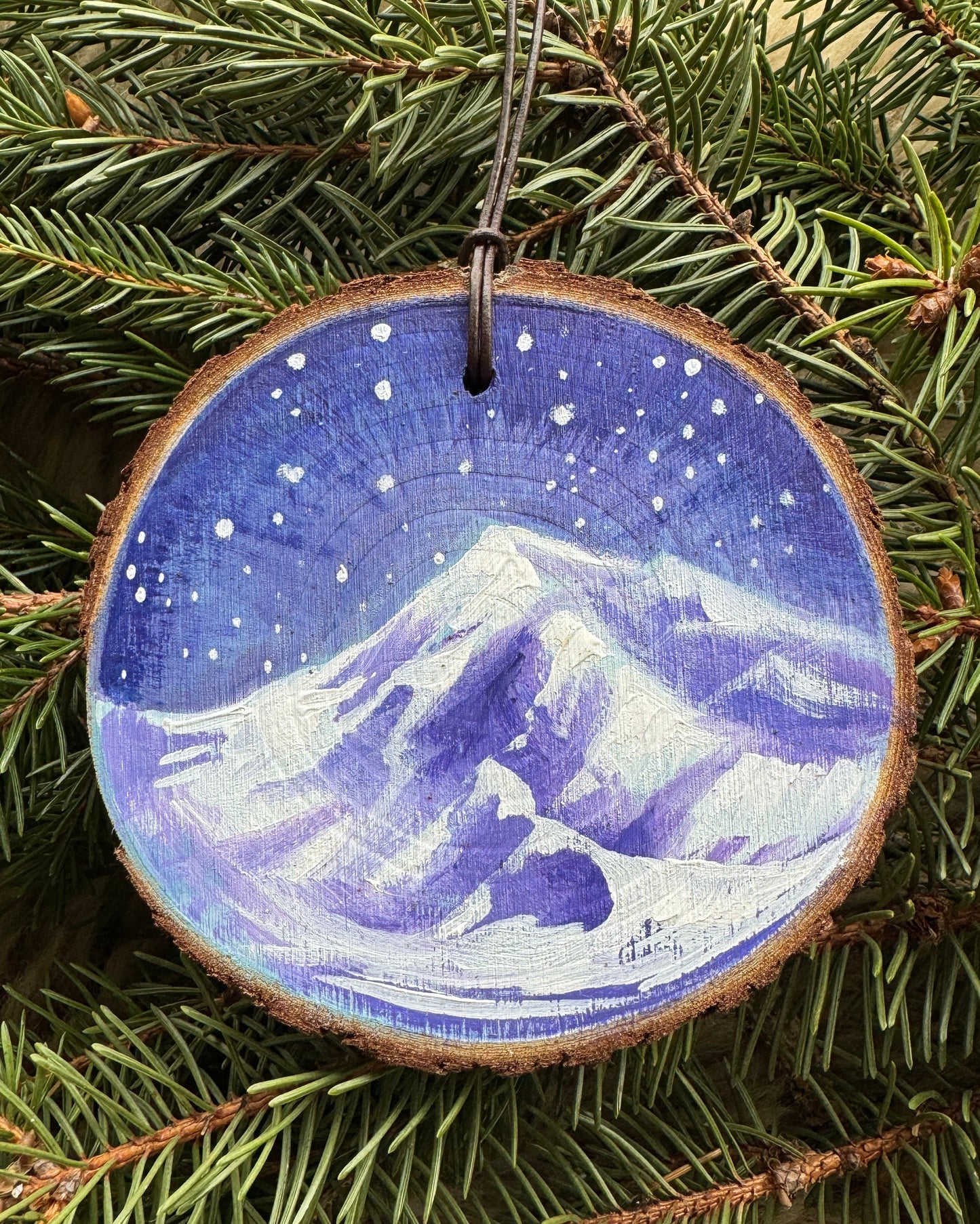Decorative ornament with a silhouette of a couple on a blue background, hanging on a Christmas tree.