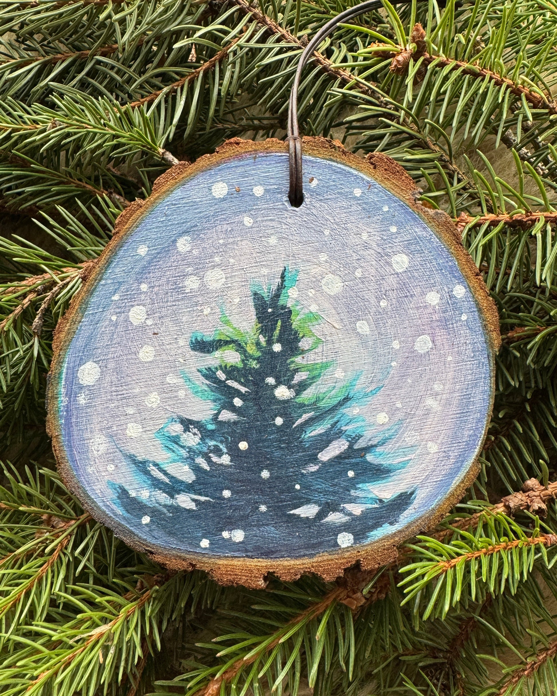 Decorative ornament with a pine tree design on a branch